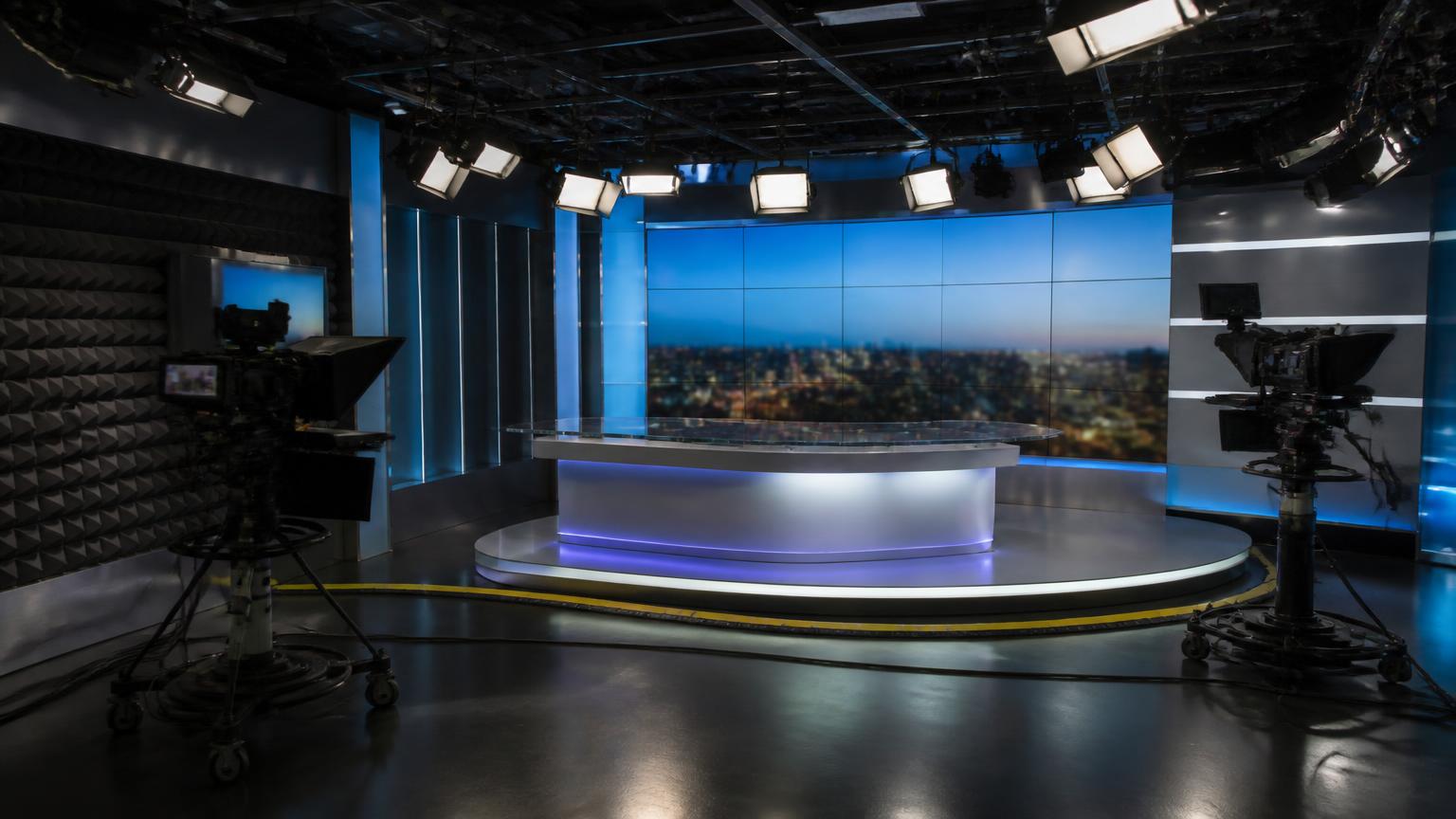 Modern live television studio of the type assessed for a national broadcaster, with lighting rig, cameras and video wall
