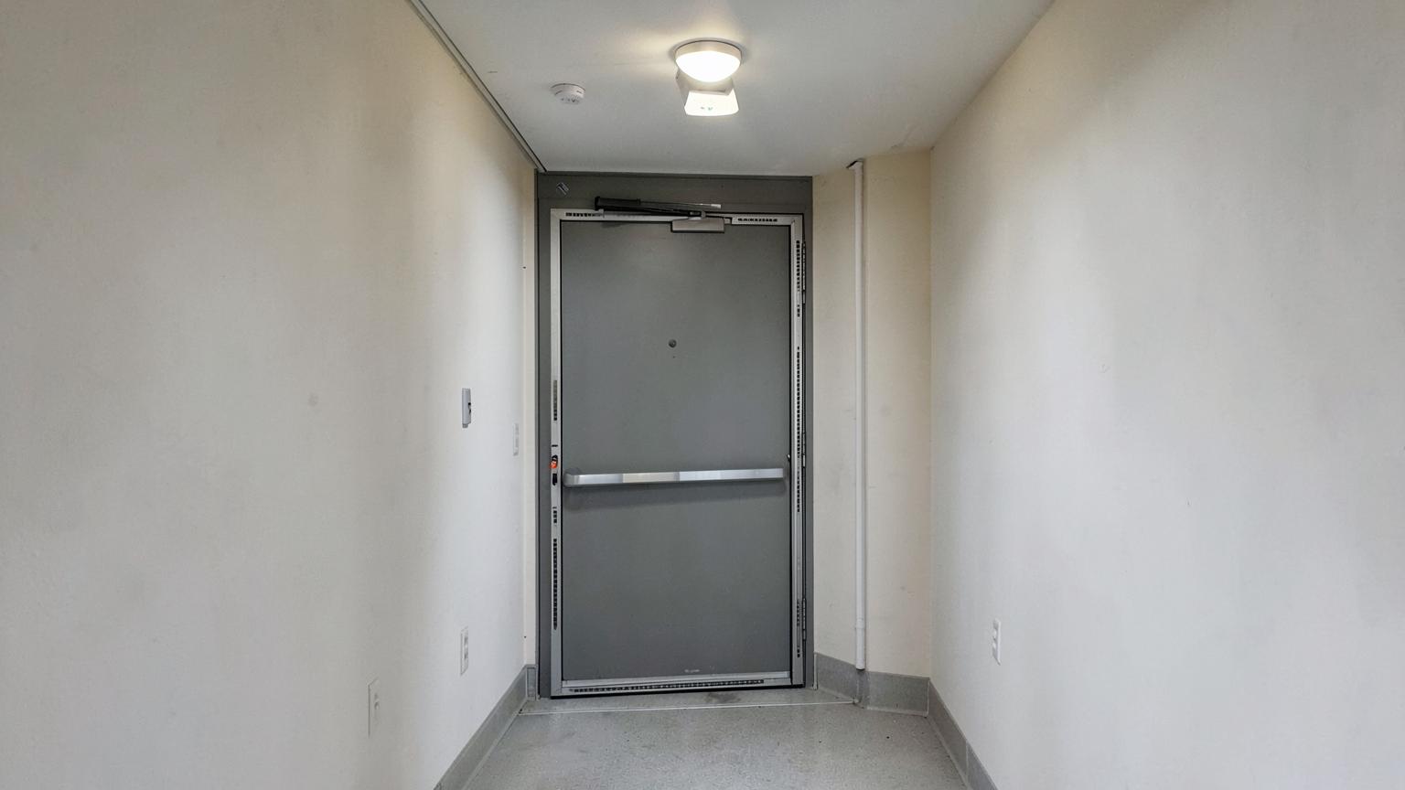 Fire door with closer and emergency light on a residential block landing