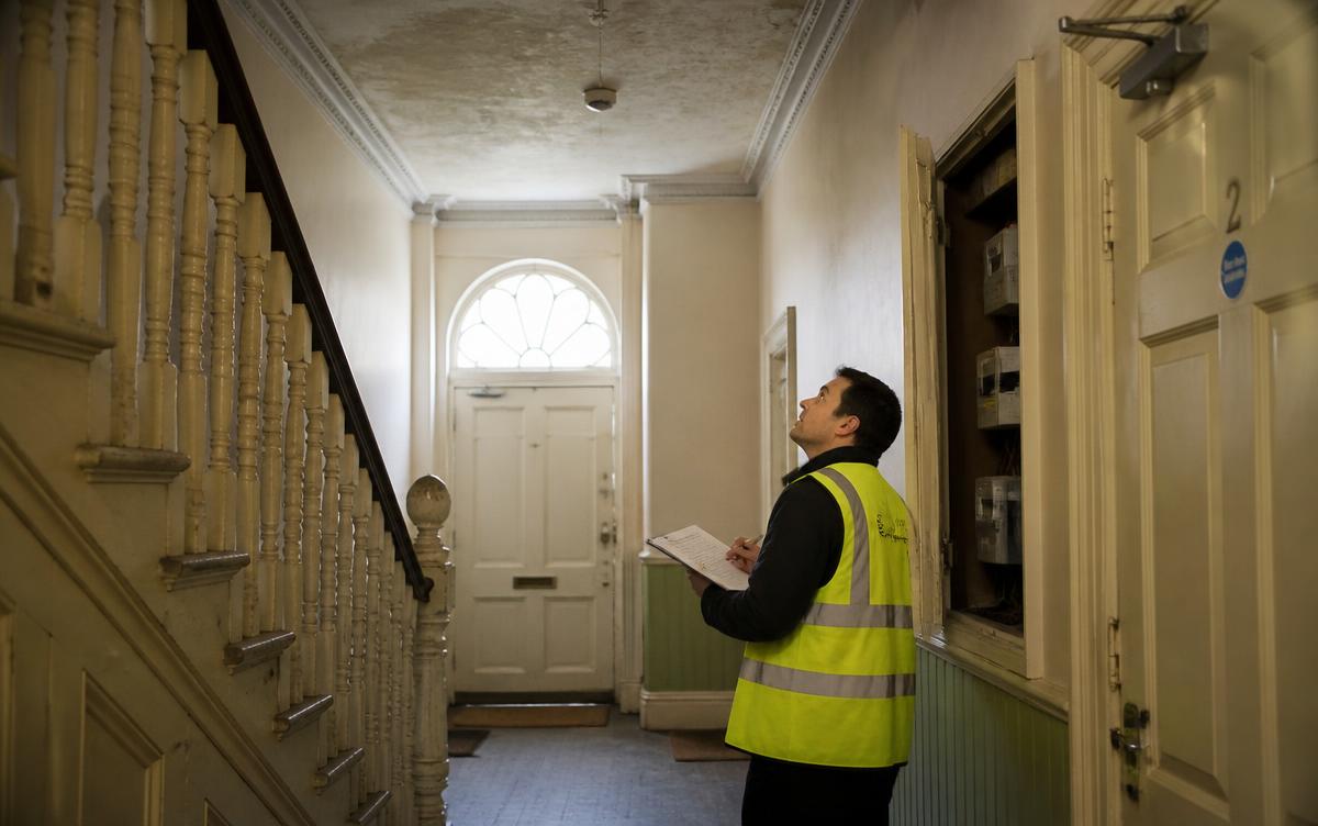 Surveyor inspecting the ceiling of a Victorian converted house communal hallway